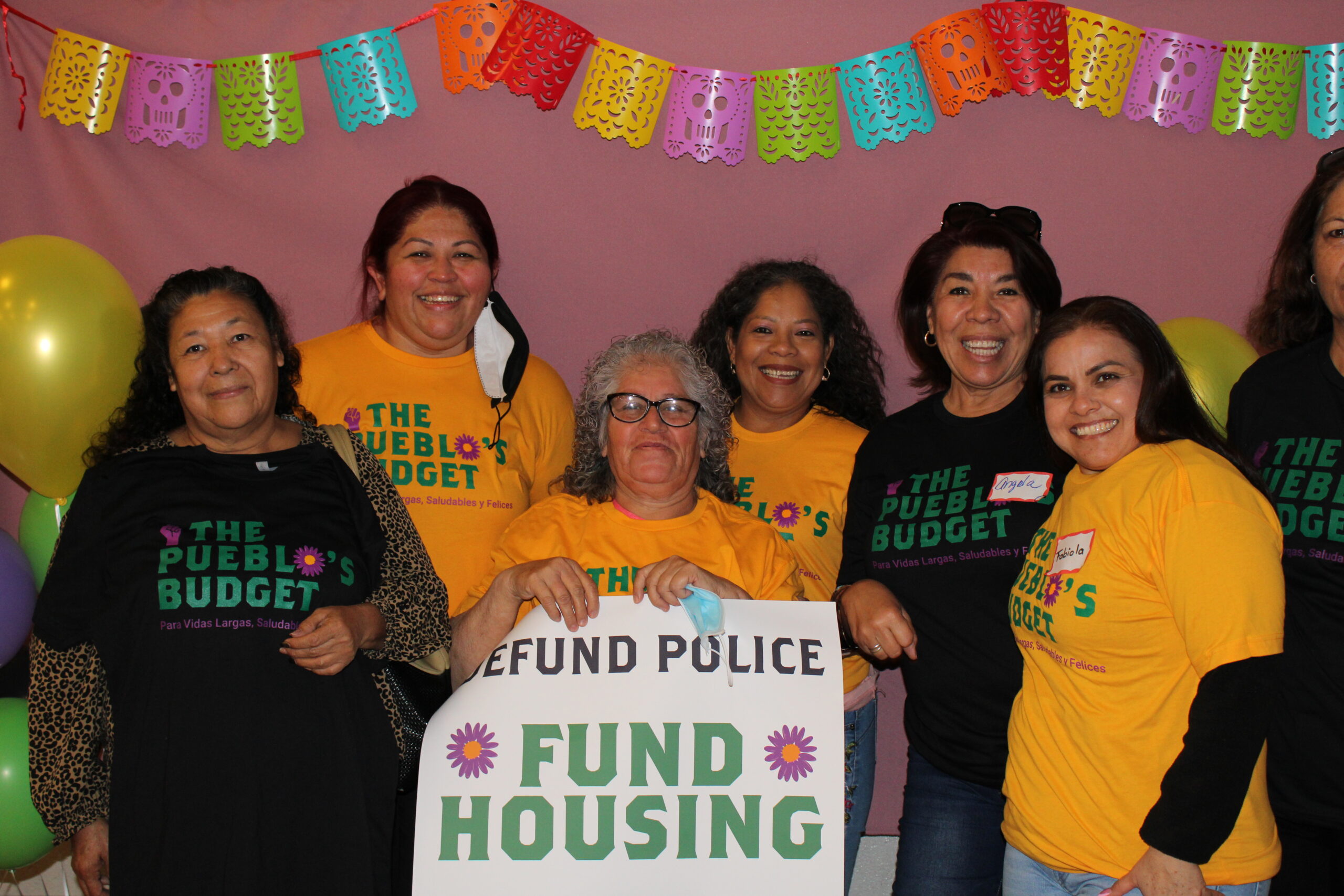 A group of women posing, a women holding up a sign that says "Defund Police, fund housing"