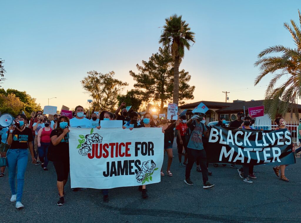 A march of people, holding signs that say "Justice for James" and "Black Lives Matter"