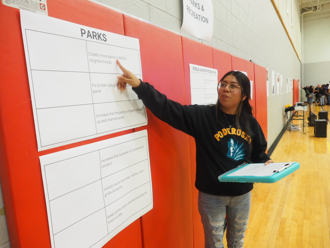 A young woman pointing to a table on a poster on the wall